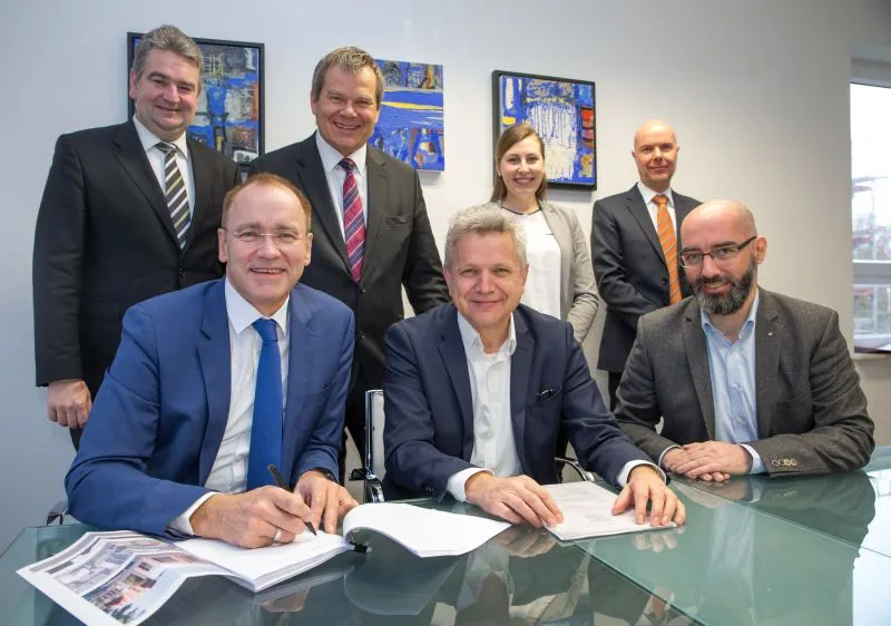 Lokschuppen wechselt Besitzer: Gunter Schneider (vorne v. l.) unterzeichnete für die Käufer der Drehscheibe Lokschuppen GbR den Vertrag, Jürgen Rausch (vorne Mitte), Geschäftsführer der als Treuhänder fungierenden GeWoBau, setzte seine Unterschrift für die Verkäuferseite darunter. Über den erfolgreichen Vertragsabschluss freuen sich mit Oberbürgermeister Dr. Thomas Spies (hinten 2. v. l.) und Bürgermeister Wieland Stötzel (hinten l.) auch Jörg Schwarz (r.), Karen Weitzel (3. v. r.) sowie Christian Gmelin (2. v. r.) von der Drehscheibe Lokschuppen GbR. Foto: Patricia Grähling, Stadt Marburg