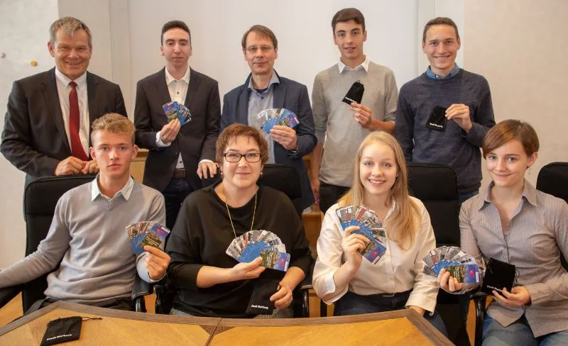 Oberbürgermeister Dr. Thomas Spies (l.), Stadträtin Kirsten Dinnebier (4.v.l.) und Steffen Maier (Mitte) stellen zusammen mit den Schülerinnen und Schülern das Kartenspiel „Marburg Code“ vor. (Foto: Patricia Grähling, Stadt Marburg)