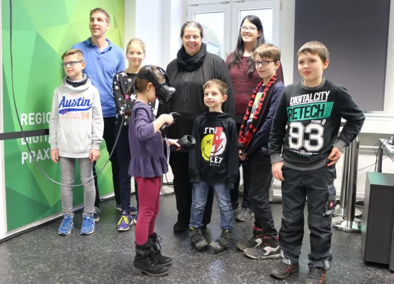 Begeistert tauchten die Kinder im SMART Teaching Lab von StudiumPlus ein in die virtuelle Welt. Die Leiterin der Stadtbibliothek, Sylvia Beiser (in schwarz) freute sich über den intuitiven Zugang der Mädchen und Jungen zu den digitalen Technologien. Jonathan Meister (hinten links) zeigte den Kindern, wie sie sich in der virtuellen Welt richtig bewegen.