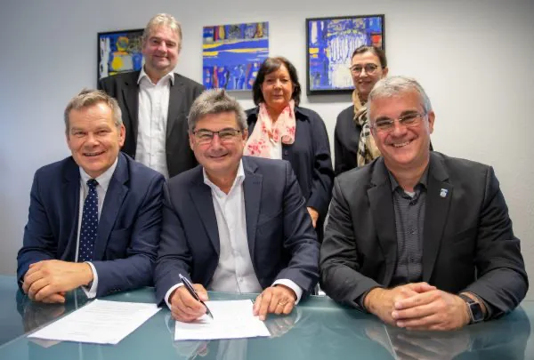 Oberbürgermeister Dr. Thomas Spies (vorne, v.l.), Bürgermeister Andreas Schulz, Bürgermeister Peter Gefeller, sowie Bürgermeister Wieland Stötzel (hinten, v.l.), Elisabeth Newton und Bianka de Waal-Schneider unterzeichnen die Verträge zur Gründung der InterKom GmbH. (Quelle: Patricia Grähling, Stadt Marburg)